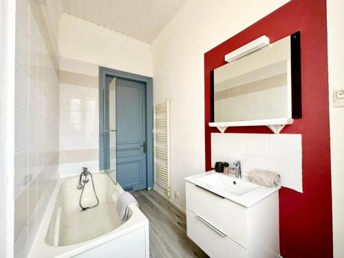 uma casa de banho com um lavatório branco e uma parede vermelha em * The Gold Time * Appartement confort * Centre-Ville em Calais