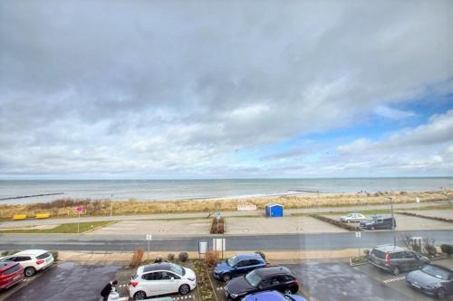 ein Parkplatz mit Autos neben dem Meer in der Unterkunft Strandhotel, App 3SH219 in Heiligenhafen