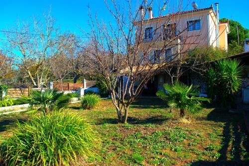 ein Haus in einem Garten mit Bäumen und Sträuchern in der Unterkunft YourLittleMiracle-PanoramicView+FirePit+Garden+BBQ in Argalasti