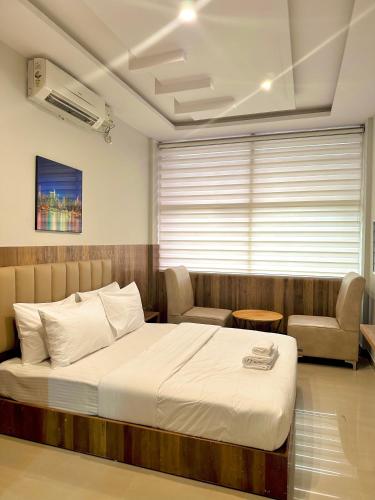 a bedroom with a bed and a chair and a window at Hotel Avenue Suites Near International Airport Bangalore in Bengaluru
