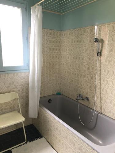 a bath tub in a bathroom with a chair and a window at Chambre 2 dans un appartement in Bourg-en-Bresse