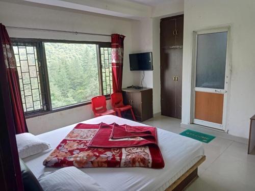 Un dormitorio con una cama con una manta roja. en Celebrations Homestay, en Shimla