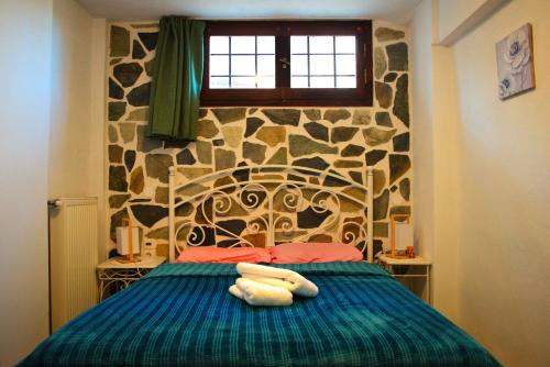 ein Schlafzimmer mit einem Bett mit einer Steinmauer in der Unterkunft YourLittleMiracle-PanoramicView+FirePit+Garden+BBQ in Argalasti