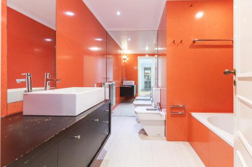 a bathroom with orange walls and a white sink at Laranjeiras Deluxe by Homing in Lisbon
