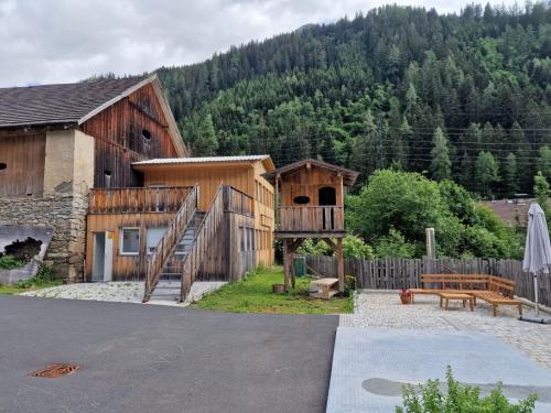 drewniany budynek z drewnianymi schodami obok domu w obiekcie Gletscher-Trail Hostel w mieście Flattach