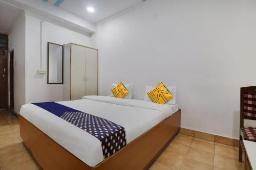 SPOT ON Apsara Hotel في حيدر أباد: غرفة نوم بسرير كبير مع مخدات صفراء وزرقاء