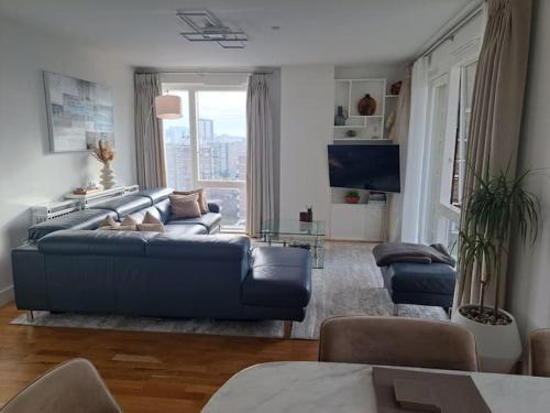 ein Wohnzimmer mit einem blauen Sofa und einem großen Fenster in der Unterkunft Cozy Double Room with Large En Suite Near Canary Wharf London with Amazing Views in a Shared Apartment in London
