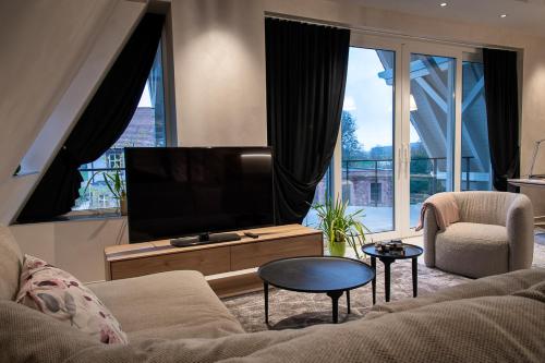 a living room with a couch and a flat screen tv at LES GITES DE LA KARLSMUHLE in Haguenau