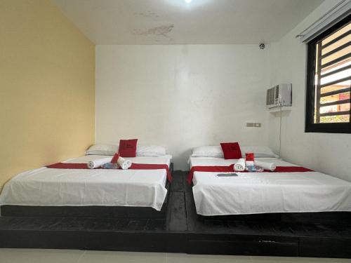 2 camas en una habitación con sábanas blancas y una ventana en RedDoorz near Mariners Legazpi, en Legazpi