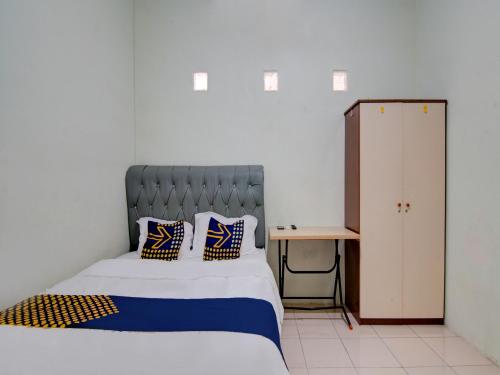 een slaapkamer met een bed met blauwe en gele kussens bij SPOT ON 92797 Awi Stay Syariah in Dumai