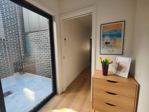 WeetangerraにあるBrand new settled house near shops with Netflixのドレッサーと大きなガラス窓が備わる客室です。