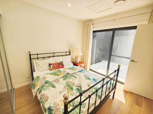 a bedroom with a bed and a large window at Brand new settled house near shops with Netflix in Weetangerra