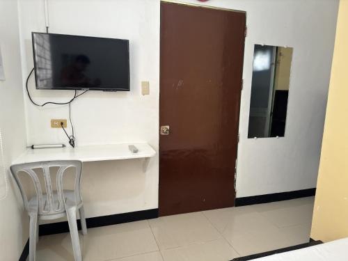 Habitación con mesa y TV en la pared. en RedDoorz near Mariners Legazpi, en Legazpi