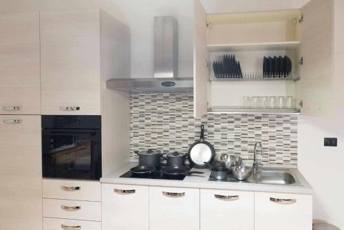 a kitchen with white cabinets and a stove top oven at CasaLina Appartamento in Santa Croce sullʼ Arno