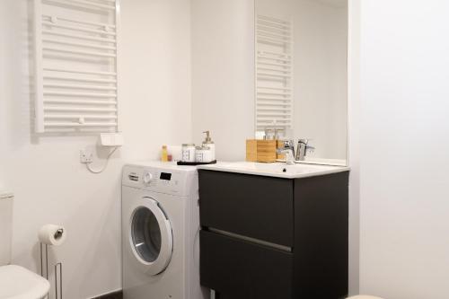 ein Badezimmer mit einer Waschmaschine und einem Waschbecken in der Unterkunft Dieu Nérée & sa vue mer in Sète