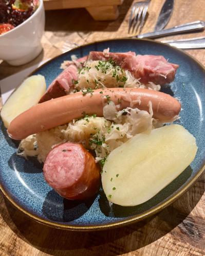 a blue plate of food with a hot dog and potatoes at LOGIS HÔTEL, CHALETS et RESTAURANT LES CHATELMINÉS in La Bresse