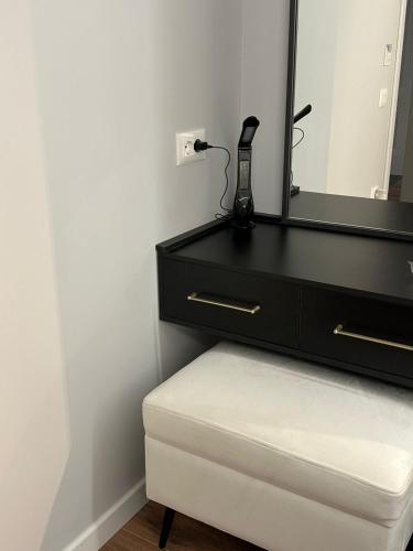 a black dresser with a mirror and a white stool at Vila Lordev in Korçë