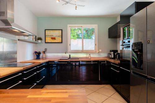 une cuisine avec des comptoirs en bois et une fenêtre dans l'établissement Villa Andria, Provençale avec Piscine, à Béziers
