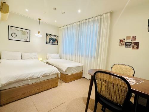 sypialnia z 2 łóżkami, stołem i biurkiem w obiekcie SSH Ikseon peter cat Hostel w Seulu