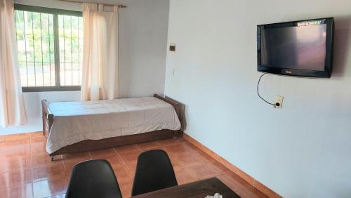 a room with a bed and a tv on the wall at Jardin del Sol in Jardín América