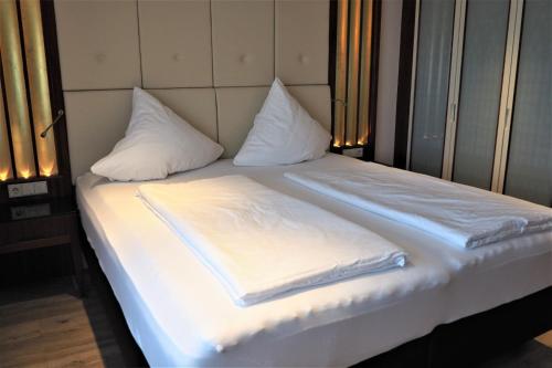 a bed with white sheets and pillows on it at Berggasthof Immenstein in Bühl