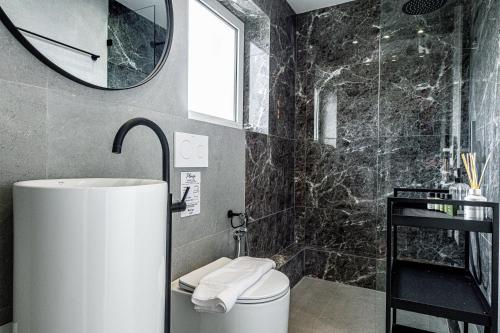 雅典的住宿－Phaedrus Living: Glyfada Seaview Luxury Penthouse，一间带卫生间、水槽和镜子的浴室