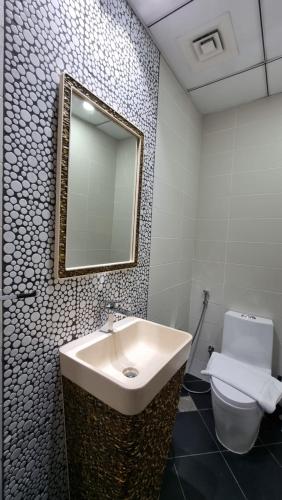 a bathroom with a sink and a toilet and a mirror at Spacious, Economical Apt Near Miralcz Garden in Dubai