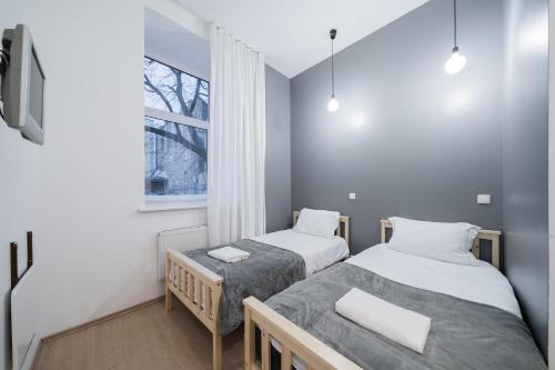 two beds in a small room with a window at Halės Self Check-in Guest House - Lollo Stay in Vilnius