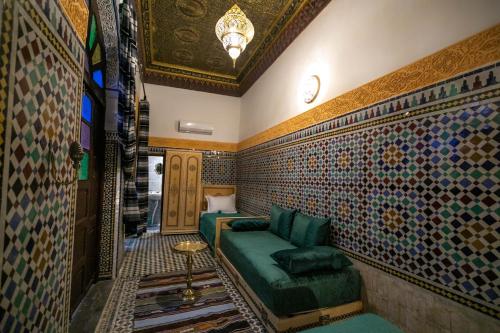 非斯的住宿－Riad Fez Qamar，客厅配有绿色沙发和一些瓷砖