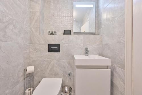 a bathroom with a sink and a toilet and a mirror at Top Floor Sandbanks Apartment with Free Parking just minutes from the Beach and Bars in Canford Cliffs