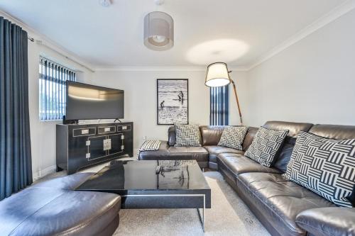 a living room with a leather couch and a tv at Top Floor Sandbanks Apartment with Free Parking just minutes from the Beach and Bars in Canford Cliffs