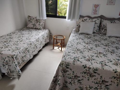 a bedroom with two beds and a chair and a window at Flat Cantinho do Paraíso in Guarajuba