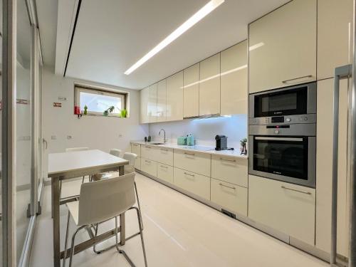 a kitchen with white cabinets and a table at Casa do Trigo - with garage in the city center in Viana do Castelo