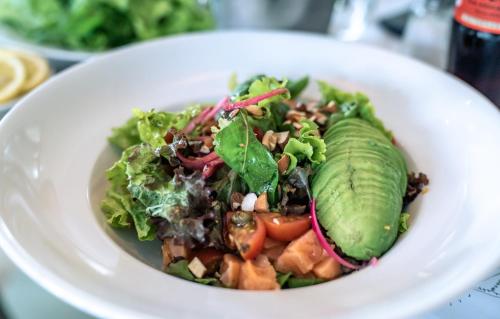 a white plate with a salad with pickles on it at Casagrande Hotel & Beach Club in José Ignacio