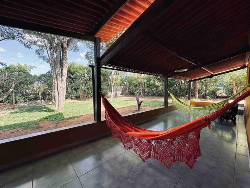 a hammock in a room with a large window at Casa Amarela - Aconchegante e Familiar in Alto Paraíso de Goiás