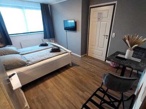 ein Schlafzimmer mit einem Bett, einem Tisch und einem Stuhl in der Unterkunft Landgasthof "Hotel zum Norden" in Jagel