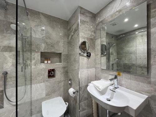 a bathroom with a sink and a glass shower at voco The Clifton Folkestone by IHG in Folkestone