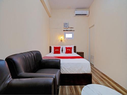 een slaapkamer met een bed en een leren stoel bij OYO 92871 Ciparay Residence in Bandung