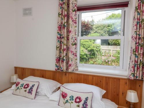 a bed with two pillows in a bedroom with a window at Poppy Cottage in Dartmouth