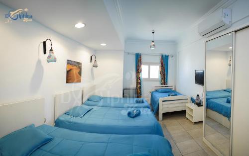 Dolphina hotel & Restaurant في دهب: غرفة نوم بسريرين ازرق ومرآة