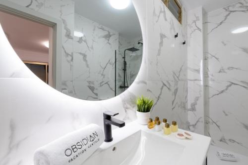 a bathroom with a white sink and a mirror at OBSIDIAN Mirador del Oceano in Puerto de Santiago