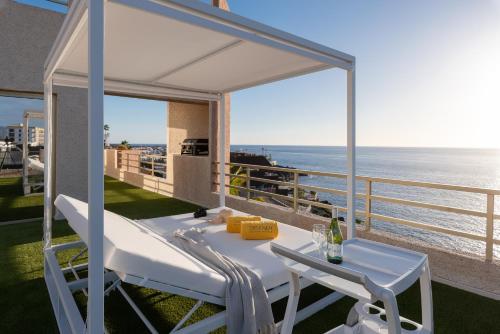Una mesa blanca y sillas en un balcón con vista al mar. en OBSIDIAN Mirador del Oceano, en Puerto de Santiago