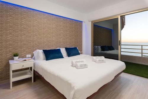 a bedroom with a large white bed with blue pillows at OBSIDIAN Mirador del Oceano in Puerto de Santiago
