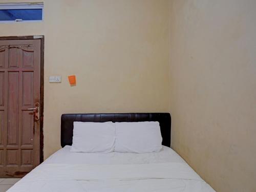 a bedroom with a bed with white sheets and a door at SPOT ON 92875 Pelita Stay in Nagoya