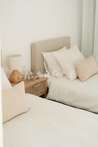 two white beds sitting next to a table with a lamp at Apartamento El Sueño in Jávea