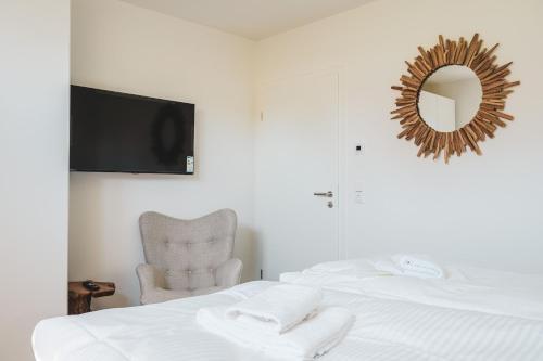 Dünenquartier Apartment 15 في زنغست: غرفة نوم بها سرير وكرسي ومرآة