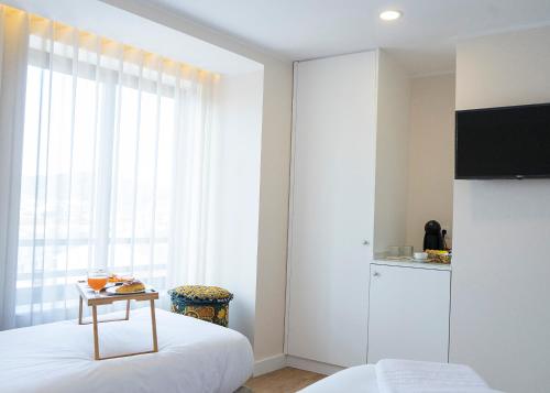 a bedroom with a bed and a table and a window at Casa da Ana Boutique Guest House in Barcelos