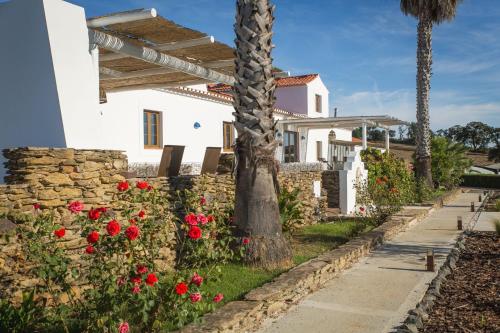 a white house with a palm tree and flowers at Monte d'avo - Turismo rural- Casa Grande in Corgos