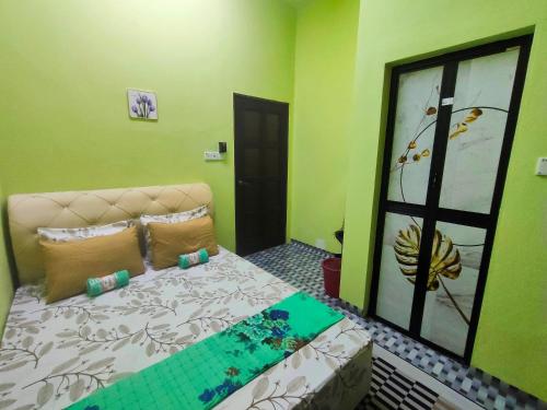 een slaapkamer met een bed in een kamer met groene muren bij Raihan Homestay B Kubang Kerian,Free Wifi in Kota Bharu