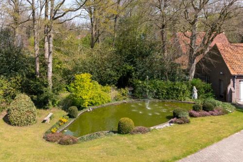 a garden with a small pond in the grass at Hotel Torenhof in Sint-Martens-Latem